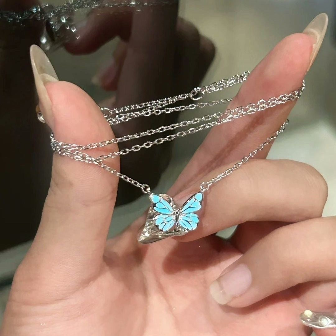 Butterfly necklace glowing aqua, held in the hand